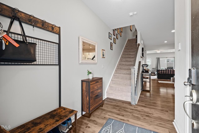foyer featuring wood finished floors, recessed lighting, baseboards, and stairs
