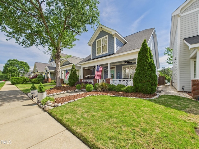 view of front of house featuring a ceiling fan, a front lawn, and covered porch