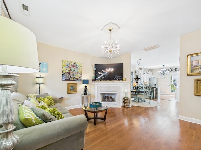 living room featuring visible vents, a fireplace, and a chandelier