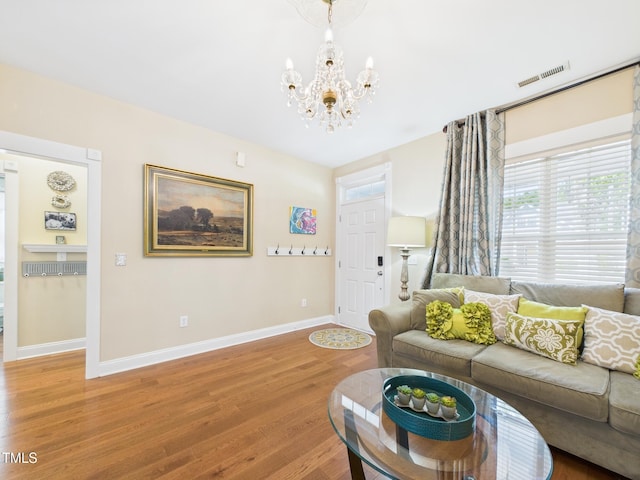 living area featuring light wood-type flooring, visible vents, baseboards, and a notable chandelier