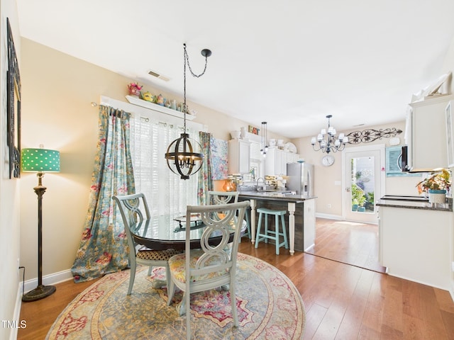 dining room featuring baseboards, an inviting chandelier, visible vents, and light wood-type flooring