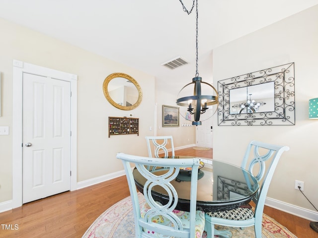dining space with visible vents, baseboards, wood finished floors, and an inviting chandelier