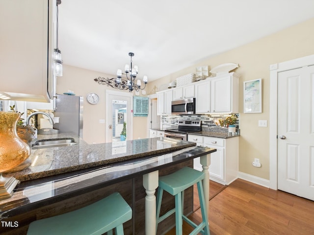 kitchen featuring a chandelier, white cabinetry, stainless steel appliances, and a sink