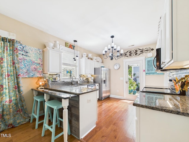 kitchen with stainless steel appliances, a sink, a wealth of natural light, and an inviting chandelier