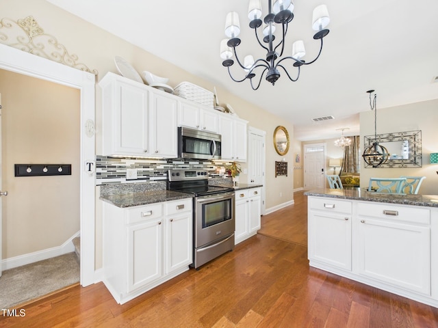 kitchen with baseboards, decorative backsplash, a chandelier, appliances with stainless steel finishes, and white cabinetry
