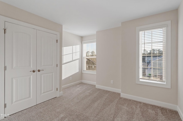 unfurnished bedroom featuring baseboards, carpet floors, and a closet
