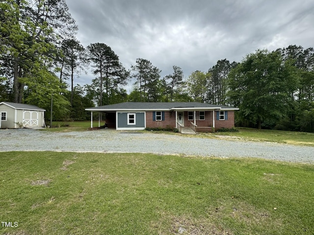 single story home featuring an outdoor structure, a storage unit, a front lawn, brick siding, and driveway