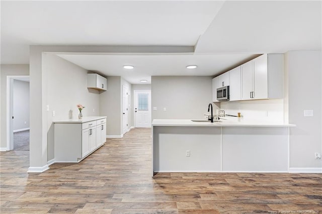 1429 Pocosin Rd, Winterville, NC 28590 - kitchen with light countertops, stainless steel microwave, a sink, light wood finished floors, and a peninsula