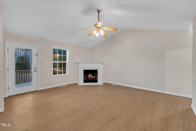 unfurnished living room featuring a ceiling fan, a fireplace, lofted ceiling, baseboards, and light wood-style floors