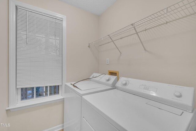 laundry area with baseboards, a textured ceiling, laundry area, and washer and clothes dryer