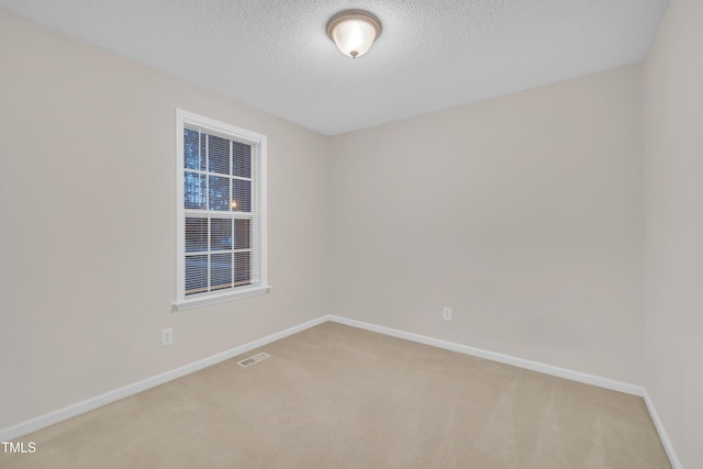 spare room with baseboards, a textured ceiling, visible vents, and carpet