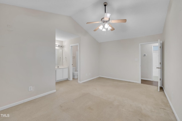 unfurnished bedroom featuring baseboards, a ceiling fan, light carpet, lofted ceiling, and ensuite bath