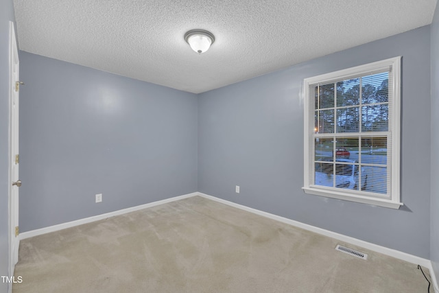 empty room featuring carpet flooring, a textured ceiling, baseboards, and visible vents