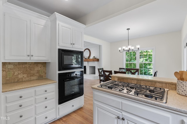 5237 Christian Light Rd, Fuquay Varina, NC 27526 - kitchen featuring black appliances, a chandelier, decorative backsplash, light wood-style floors, and white cabinetry