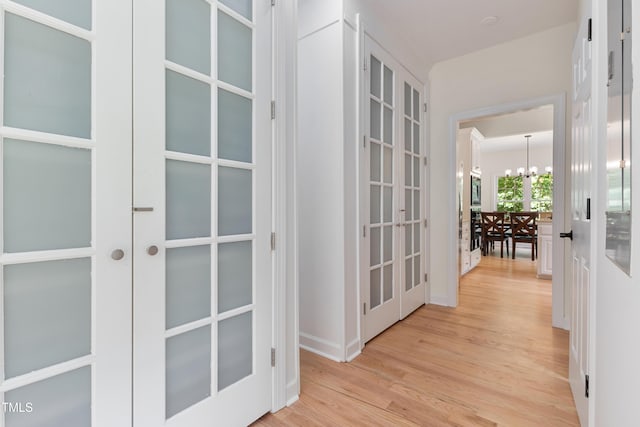 5237 Christian Light Rd, Fuquay Varina, NC 27526 - hallway with french doors, a chandelier, and light wood-style flooring