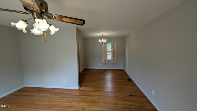 unfurnished room featuring baseboards, visible vents, light wood-style flooring, and ceiling fan with notable chandelier