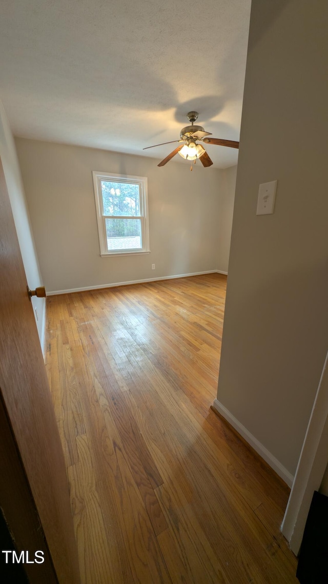 unfurnished room featuring baseboards, a ceiling fan, and light wood-style floors