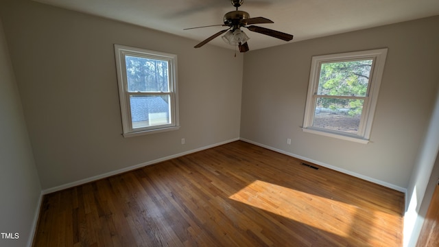 unfurnished room with ceiling fan, baseboards, visible vents, and wood finished floors