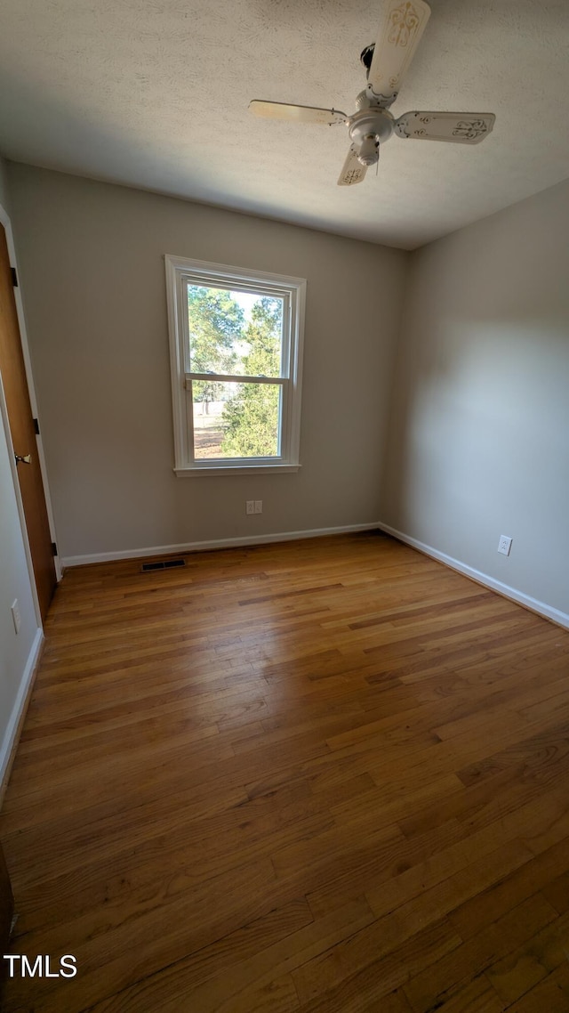 unfurnished room featuring baseboards, ceiling fan, wood finished floors, and visible vents