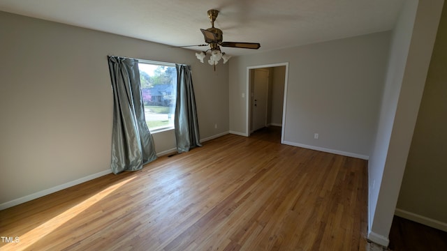 spare room with light wood-type flooring, baseboards, and ceiling fan