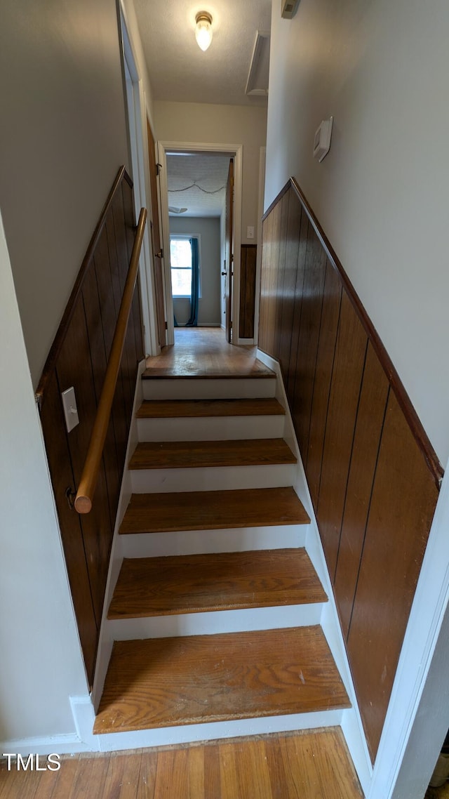 stairway with wainscoting and wood finished floors