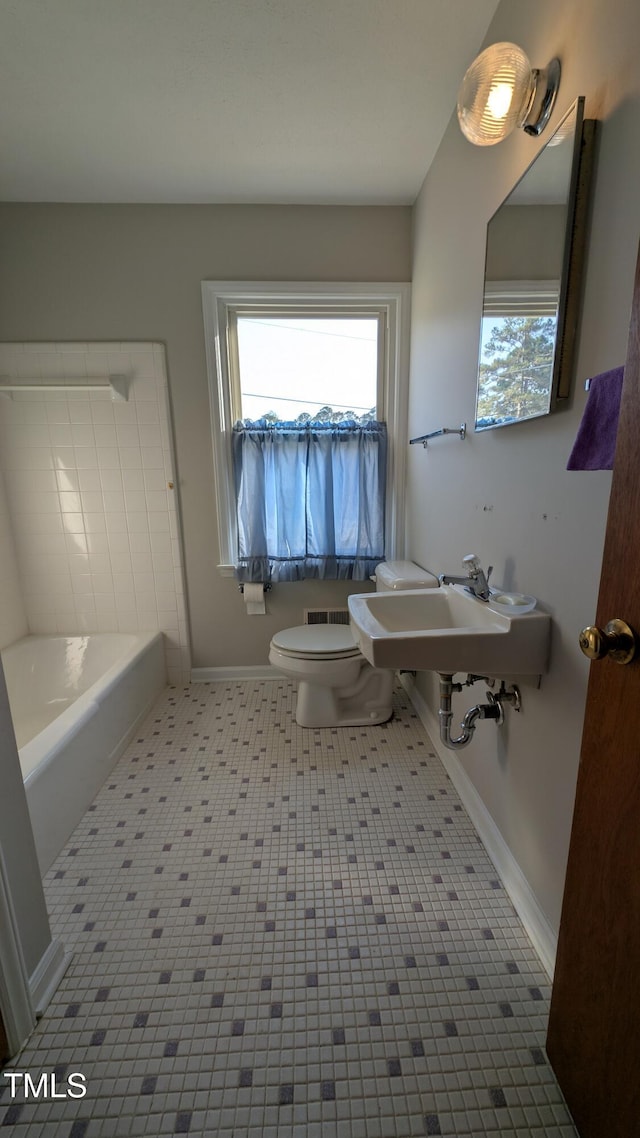 full bathroom with a sink, baseboards, plenty of natural light, and toilet