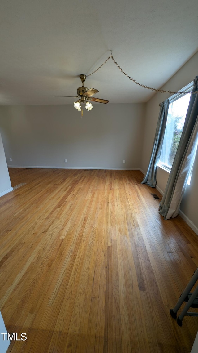 spare room featuring ceiling fan, baseboards, and light wood-style floors