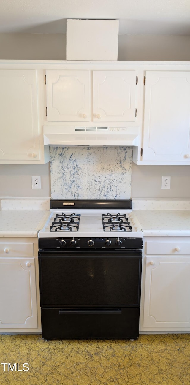 kitchen featuring light countertops, white cabinetry, under cabinet range hood, and black gas range oven