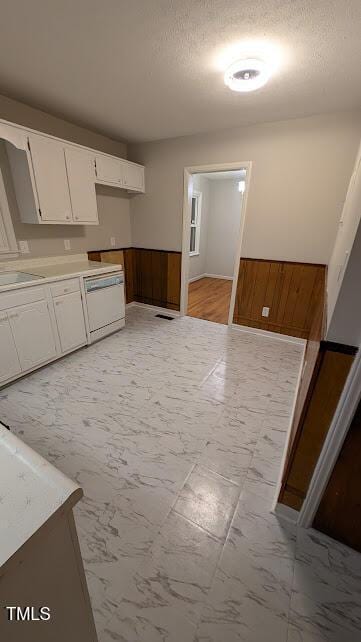 5240 Chesapeake Rd, Fayetteville, NC 28311 - kitchen with dishwasher, a wainscoted wall, white cabinetry, light marble finish floors, and wooden walls