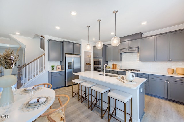 kitchen with a sink, light wood-type flooring, stainless steel appliances, custom range hood, and a breakfast bar area