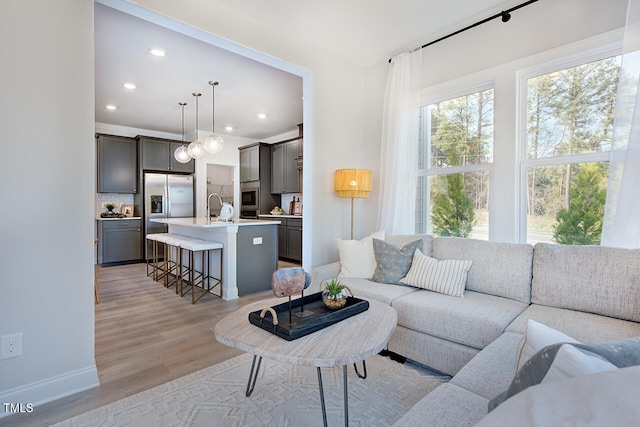 living room featuring light wood finished floors, baseboards, and recessed lighting