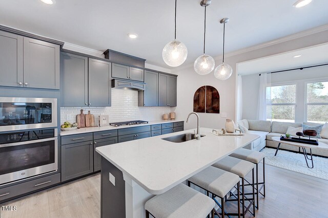 kitchen featuring a sink, a breakfast bar, under cabinet range hood, and stainless steel appliances