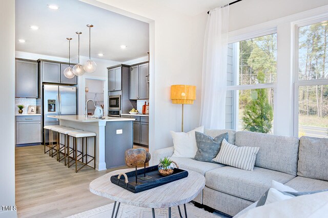 living room featuring light wood-style floors, crown molding, and recessed lighting