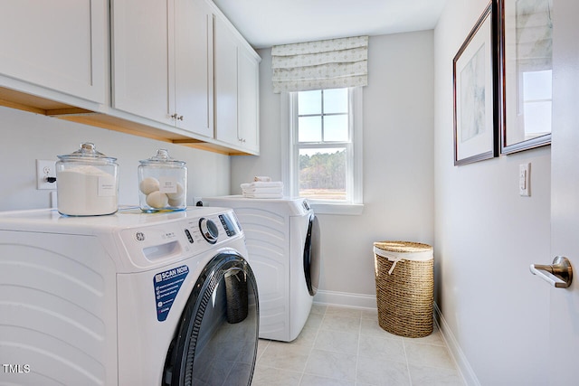 clothes washing area with washer and dryer, light tile patterned floors, baseboards, and cabinet space