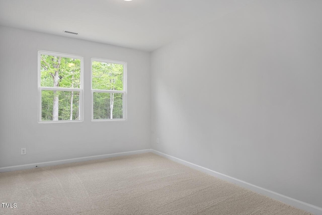 empty room featuring carpet floors, visible vents, and baseboards