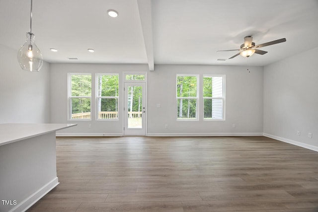 unfurnished living room with baseboards, a ceiling fan, and plenty of natural light