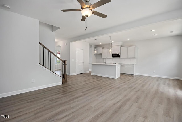 unfurnished living room featuring a ceiling fan, light wood-style flooring, recessed lighting, and baseboards