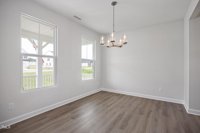 empty room with visible vents, baseboards, a chandelier, and dark wood-type flooring