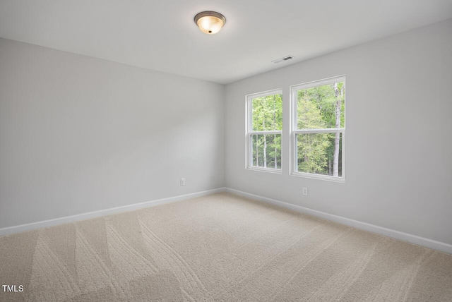 empty room with baseboards, visible vents, and carpet