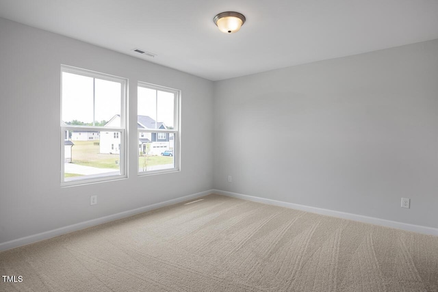 empty room with visible vents, light colored carpet, and baseboards