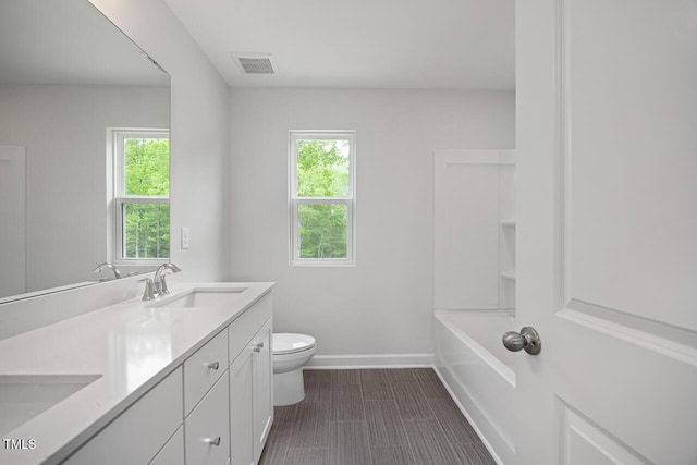 bathroom featuring a sink, toilet, double vanity, visible vents, and baseboards