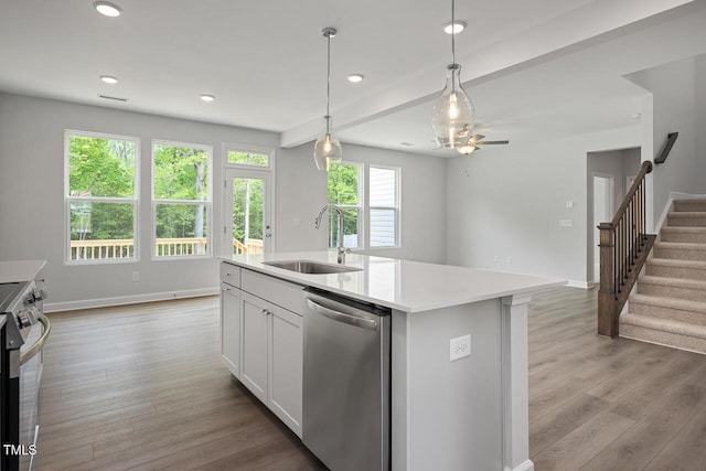 kitchen with hanging light fixtures, stainless steel appliances, light countertops, a sink, and light wood-type flooring