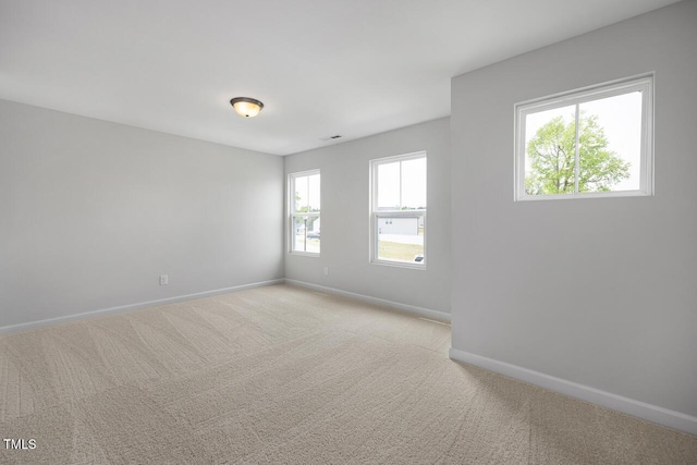 unfurnished room with baseboards, visible vents, and light carpet
