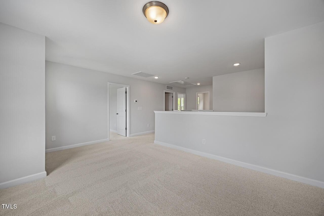 empty room featuring baseboards, visible vents, attic access, and light carpet