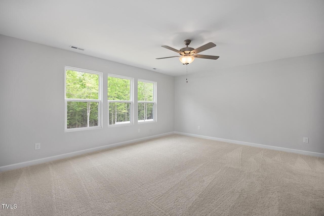 empty room with a ceiling fan, visible vents, light carpet, and baseboards