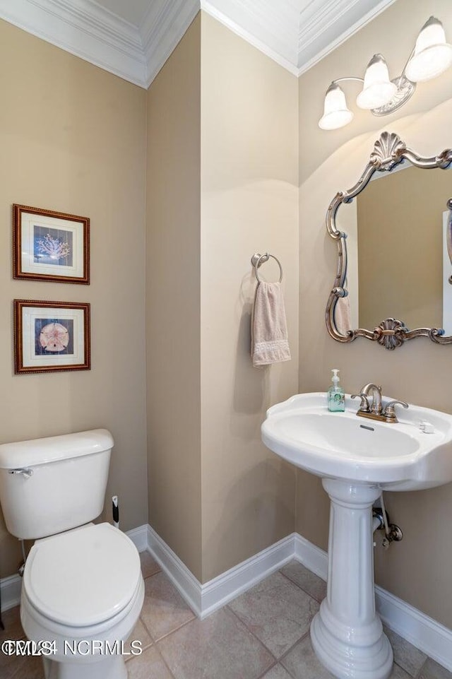 bathroom featuring baseboards, ornamental molding, toilet, and tile patterned floors