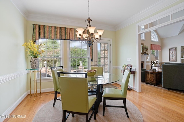 dining room featuring ornamental molding, light wood-style flooring, a notable chandelier, and baseboards