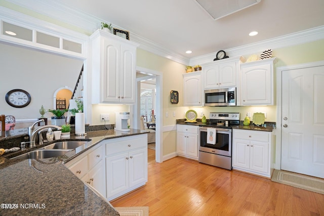kitchen featuring white cabinets, light wood-style flooring, a sink, and stainless steel appliances