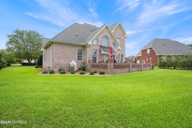 back of property featuring a lawn, a shingled roof, and brick siding