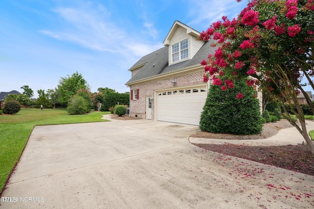 view of property exterior with brick siding, driveway, a shingled roof, and a yard